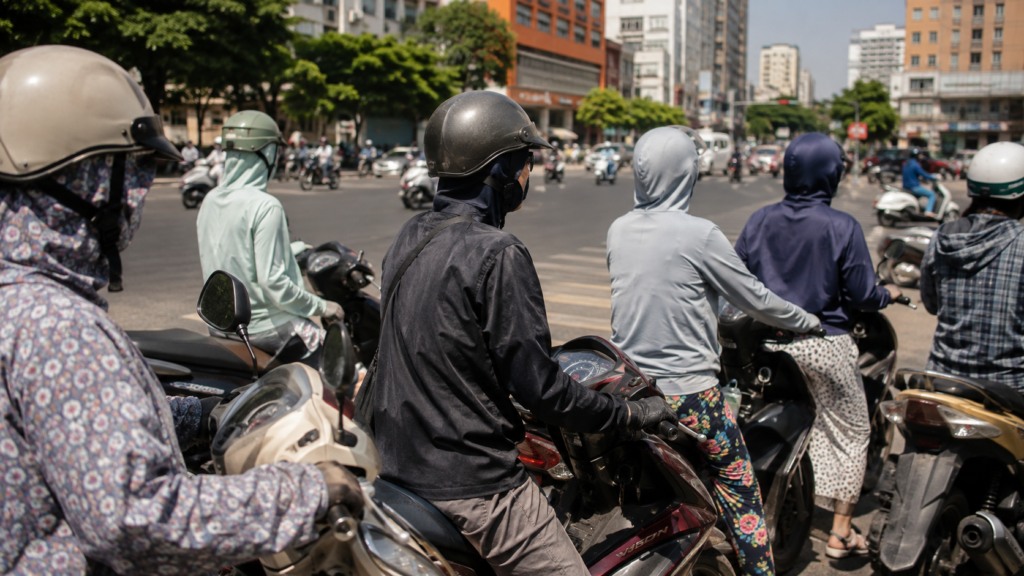 Motorbike riders in long sleeves, gloves and face masks at a city intersection in midday sun