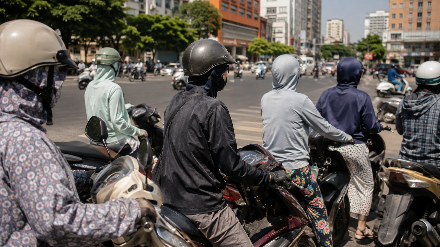 Motorbike riders in long sleeves, gloves and face masks at a city intersection in midday sun